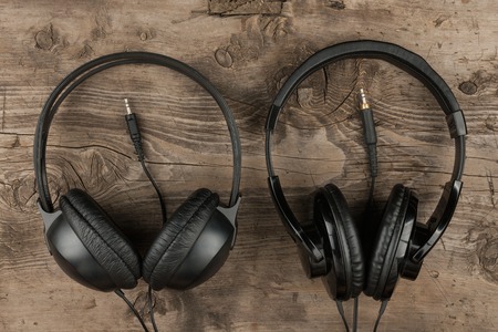 Two headphones and the cord symbolic of a love for music on an antique wooden texture background, top viewの写真素材
