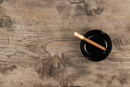 Glass ashtray with cigar stands on a wooden surface, can be used as backgroundの写真素材