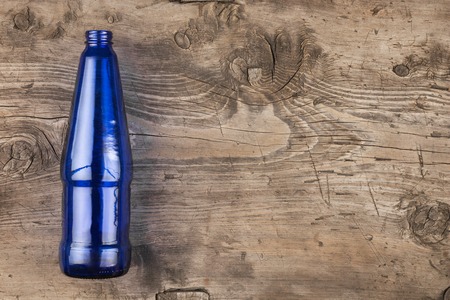 Blue glass bottle lying on an old wooden surface, top viewの写真素材