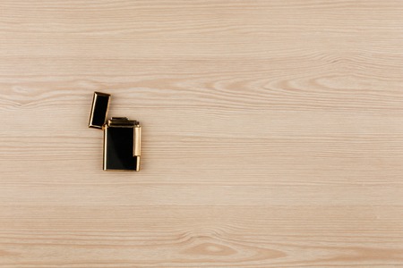 Luxury gold lighter lying on a wooden surface. With room for your text. View from aboveの写真素材