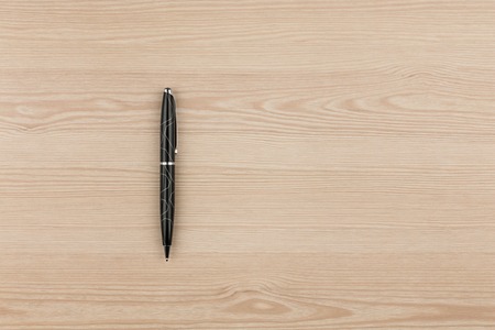 Black ballpoint pen lies on a wooden texture, with place for your textの写真素材