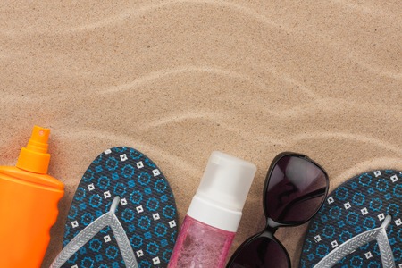 Accessories for the beach lying on the sand, with place for your text. View from above