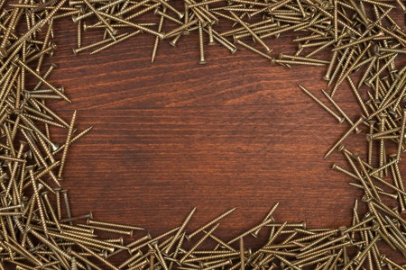 Frame of new black screws lying on a wooden surface. With space for textの写真素材