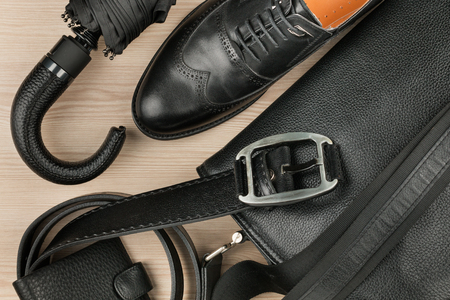 Classic black shoes, briefcase, belt and umbrella on desk. View from above. Ideas and concepts of business and fashion.の写真素材