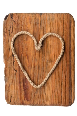 Classic heart made of rope lies on the old wooden frame, isolated on white background. Space for text. View from aboveの写真素材