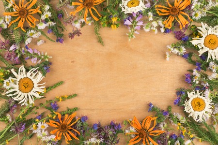 Dry and fresh wildflowers along the edges of the wooden background. View from aboveの写真素材