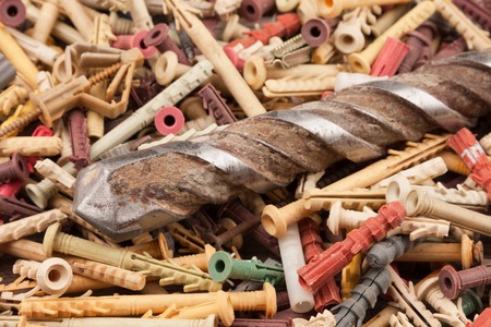 Old drill for drilling concrete lies on a pile of dowels. Close-up