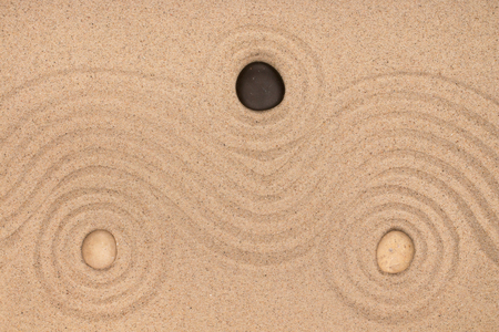 Three stone lies in the center of a circle of sand. Texture of sand. View from aboveの写真素材