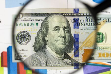 Close-up of hundred dollars through a magnifying glass. Business background. Money research concept. Top viewの写真素材