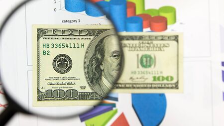 Magnifying glass and money - business background. Hundred dollar bill under a magnifying glass is...