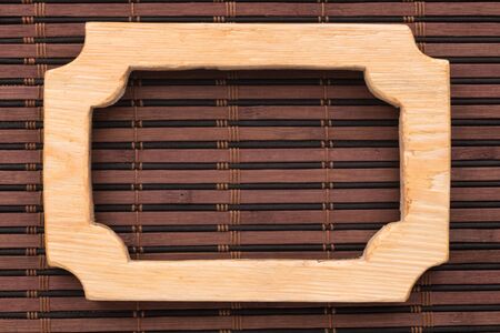Beautiful frame, sign board cut from a solid board, lies on a bamboo mat. Close-up. Top view
