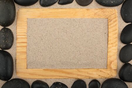 Wooden frame and stones on the sand. Copy space. Top viewの写真素材