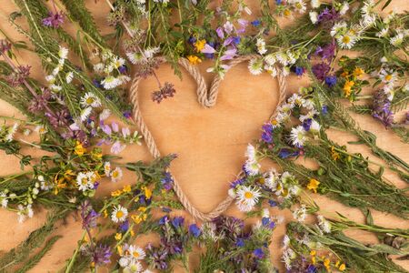 Heart made of rope in the center of wildflowers. View from above. Festive backgroundの写真素材