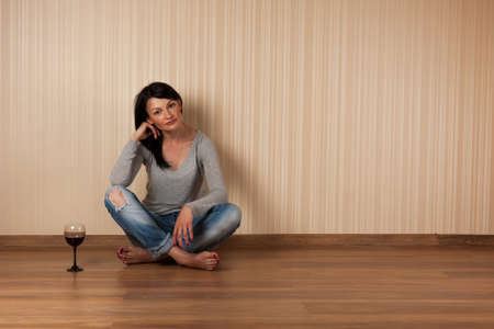 Young beautiful brunette relaxes with a glass of red wine. Relaxation, romance, leisure, lifestyle. The woman is enjoying red wine.の写真素材