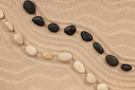 Two wavy lines of stones lying on the sand of the beach. Top view. Copy space.