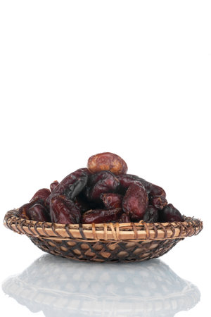 Heap of dry dates in a wooden plate. Isolated on white background.の写真素材