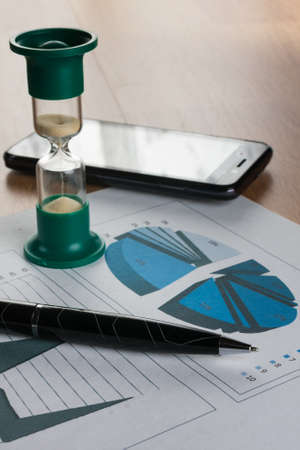 Business background. Pen, chart, hourglass and telephone. Close-upの写真素材