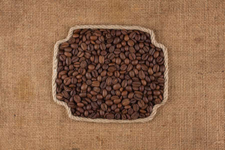 Frame made of rope with a whole, roasted coffee bean. With space for design, text place. Top viewの写真素材