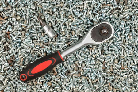 Screwdriver is lies on a pile of screws. Tools, screws made of steel. Industrial background. Top viewの写真素材