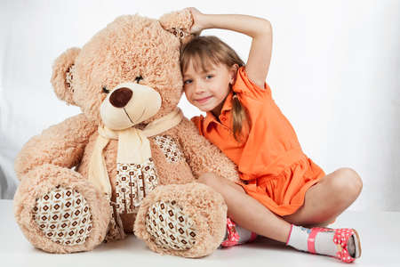 Cute little girl playing with her friend big fur bear. Baby girl hugging her teddy bearの写真素材
