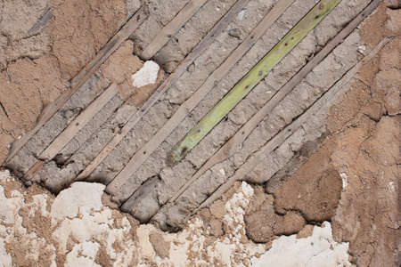 Fragment of an old destroyed wall with fallen off plaster and wooden lath in abandoned house. Close-upの写真素材
