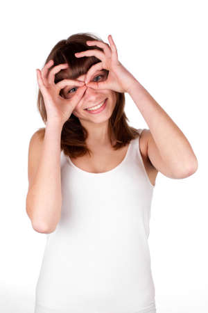Young woman makes glasses with fingers. The girl looks in impromptu glasses, hand gesture. Isolated on white background.の写真素材