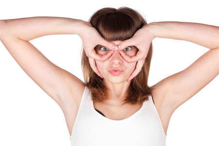 Young woman makes glasses with fingers. The girl looks in impromptu glasses, hand gesture. Isolated on white background.の写真素材