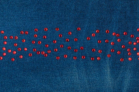 Red rhinestones lying in a line on worn denim. With space for design, text place. Top viewの写真素材
