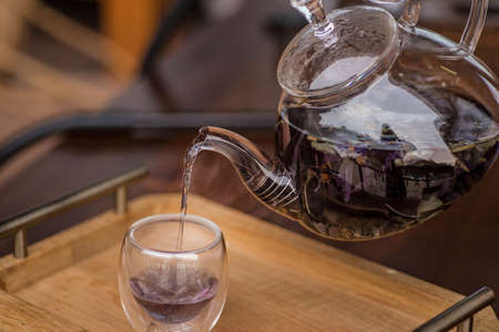 Purple floral herbal tea is poured from the brewer into the cup.の写真素材