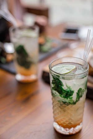 Fresh summer cocktails with bubbles, lime, mint and red berries are on the table at the sunset....
