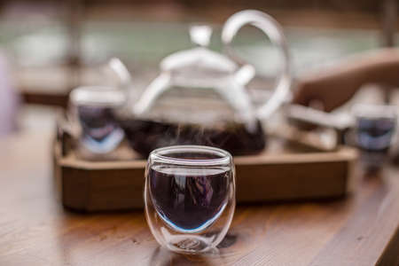 Purple floral herbal tea is poured from the brewer into the cup.