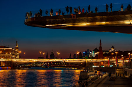 Russia, Moscow, 12 sept 2023. "Soaring bridge" with people above Moscow river in the park "Zaryadye". Evening sunset landscape scenery view on embankment Moscow river and Kremlin with reflections in water flowのeditorial素材