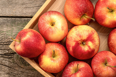 Fresh red apples in a wooden box on a rustic wooden tableの写真素材