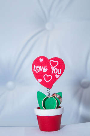 Wedding rings closeup on the petal of the artificial flower in the shape of a heartの写真素材