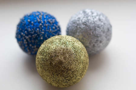 three multicolored christmas balls on a white background close-up.の写真素材