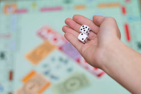 female hand throws dice in a board game close up.