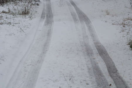 Winter puddles and snow slush on road with traces of tires during the thaw.の写真素材