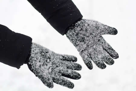 female black gloves with snow close up.の写真素材