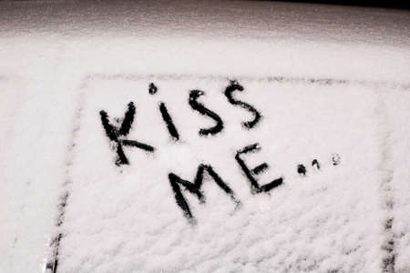 frozen car glass on a winter day with the inscription kiss me.の写真素材