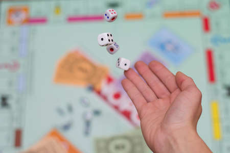 female hand throws dice in a board game close up.の写真素材