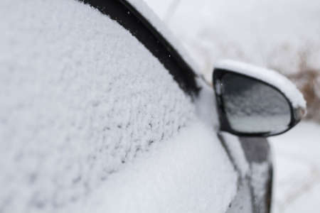 Snow covered side view mirror of a modern car.の写真素材