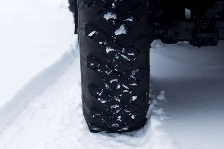 Closeup of car tires in winter on the road covered with snowの写真素材