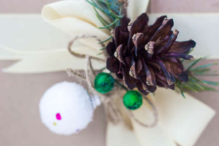 Gift box with ribbons decorations in the form of cones and branches of a Christmas tree close-up.の写真素材