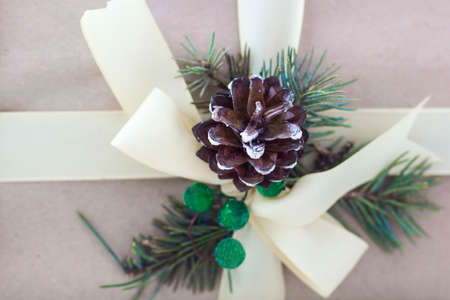 Gift box with ribbons decorations in the form of cones and branches of a Christmas tree close-up.の写真素材
