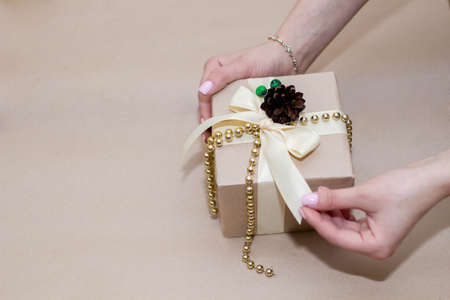 women's hands hold a gift in cardboard packaging and decor of cones.