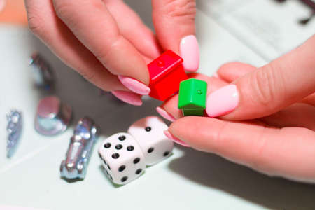 Female hands holding gaming chips, houses and dice close-up