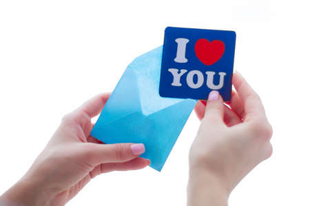 Hand of girl writing love letter on Saint Valentines Day.Handmade postcard with red heart shaped...