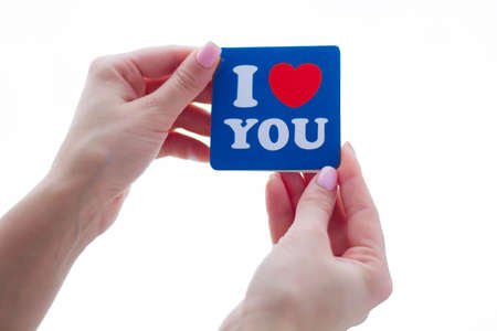 Hand of girl writing love letter on Saint Valentines Day.Handmade postcard with red heart shaped...