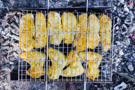Cooking meat on the grill in the open air on the fireの写真素材