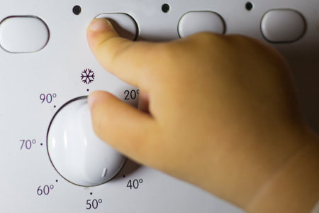 A childs hand presses a button on a washing machineの写真素材